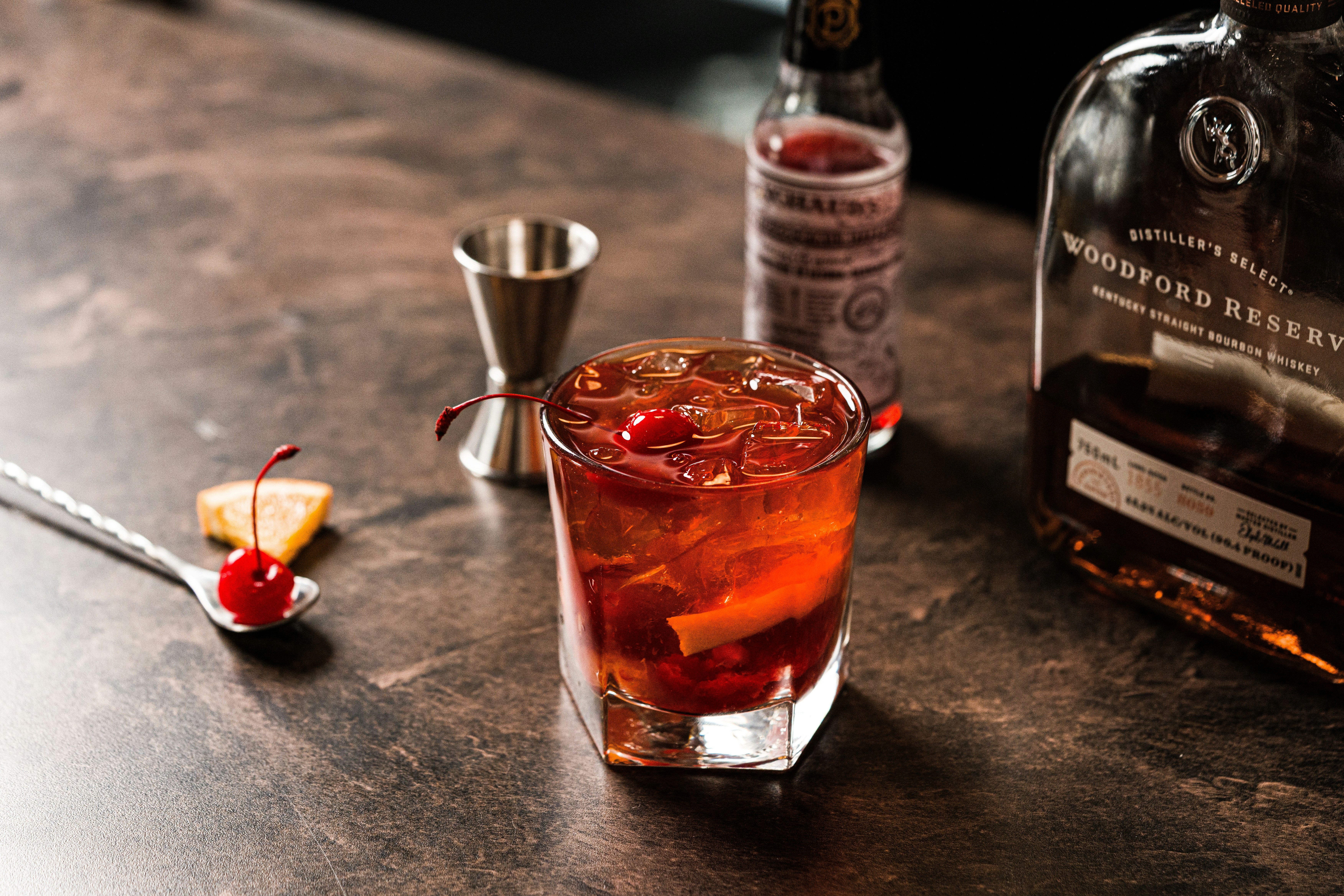 An Old Fashioned cocktail on a dark bar surface